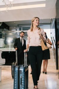 Smiling guest walking through a Dubai hotel lobby with rolling suitcase