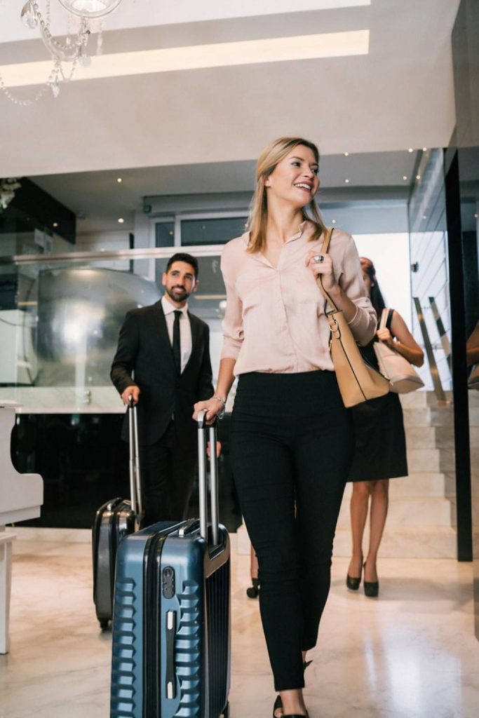 Smiling guest walking through a Dubai hotel lobby with rolling suitcase